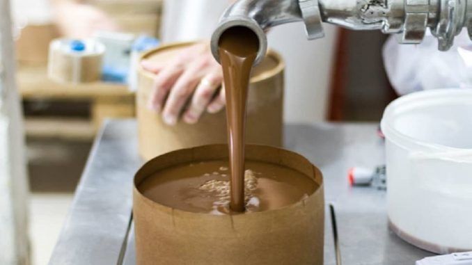 Industrial production of Argentinian dulce de leche being poured into packaging container.