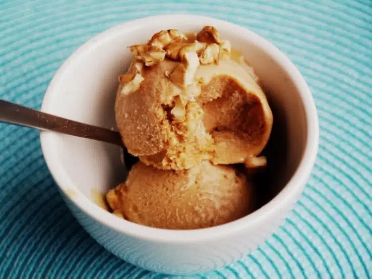 Homemade dulce de leche ice cream served in a white bowl with chopped nuts