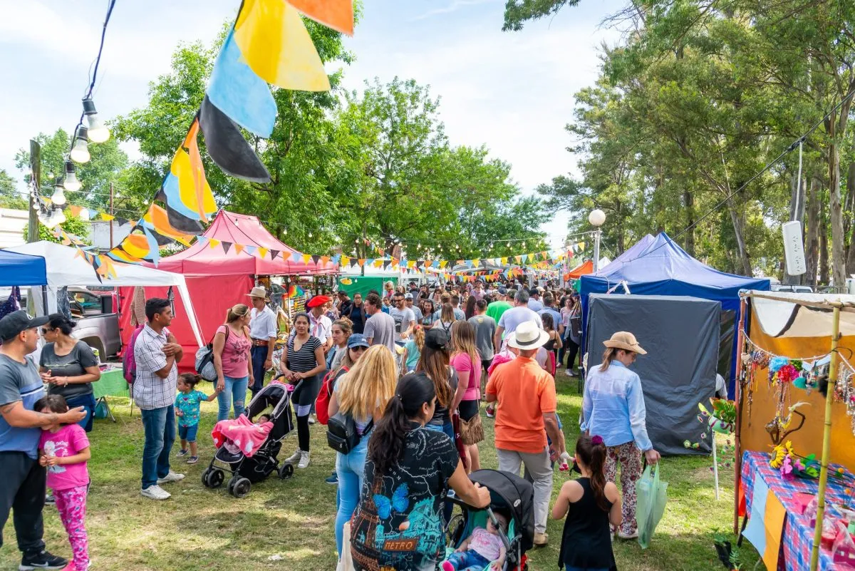 Feria cultural argentina al aire libre en verano 2025 en Estados Unidos, con puestos de artesanías, comida típica y familias disfrutando del evento.