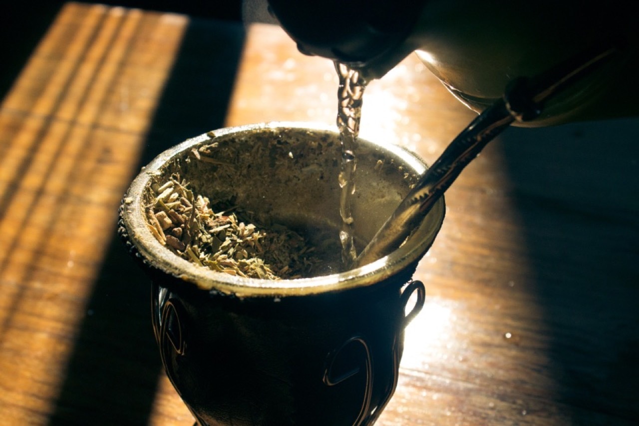 Pouring hot water into a traditional Argentine mate gourd with yerba mate and bombilla