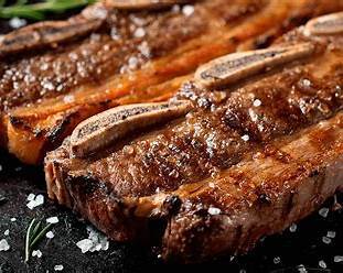 Grilled Argentinian beef ribs served with traditional chimichurri sauce on a wooden board