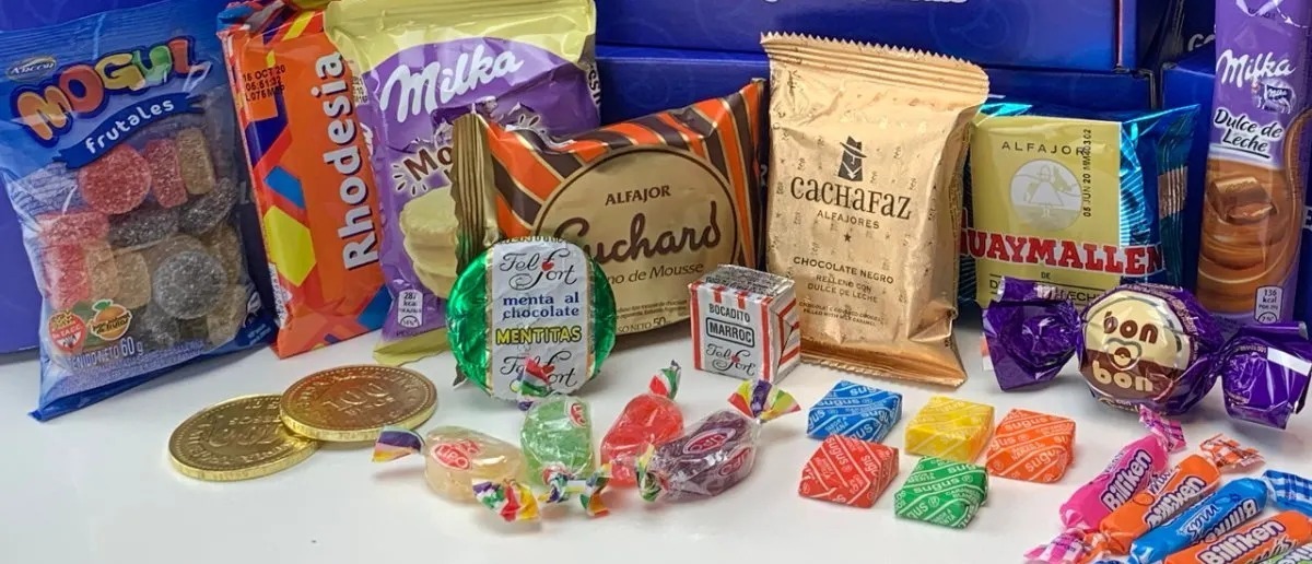 Classic Argentine candy assortment featuring alfajores, Bon o Bon chocolates, Cachafaz, Guaymallén, Milka dulce de leche bars, Sugus candies, and traditional Argentine sweets